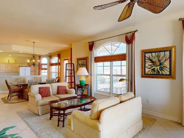 Living room featuring light tile patterned flooring and ceiling fan with notable chandelier