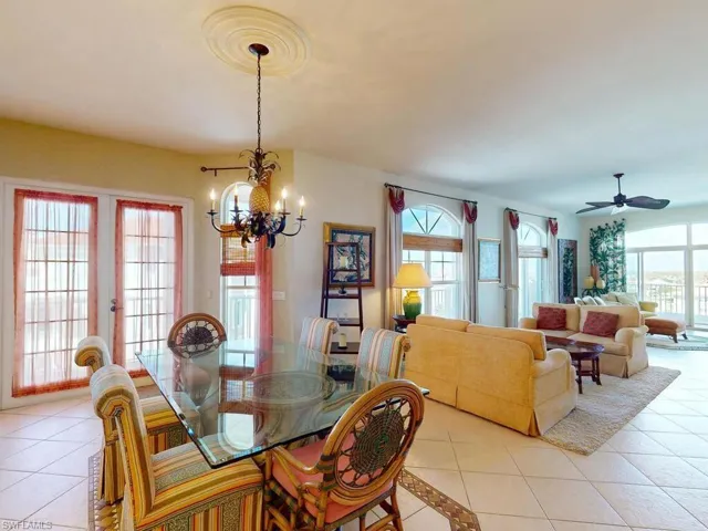 Tiled dining room featuring french doors, ceiling fan with notable chandelier, and a wealth of natural light