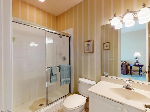 Bathroom featuring a shower with door, vanity, and toilet