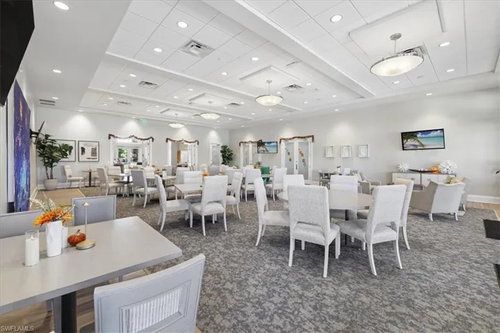 Expansive common area featuring a coffered ceiling with inset recessed lighting, decorative chandeliers, wall-to-wall carpeting, and multiple sets of glass-paneled double doors