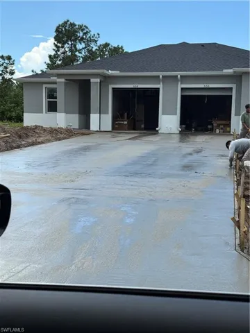 View of front of home featuring driveway, stucco siding, a garage, and roof with shingles