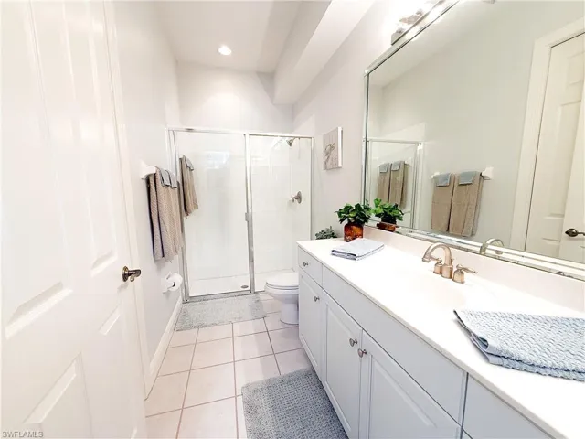 Bathroom featuring vanity, light tile patterned floors, and a shower stall