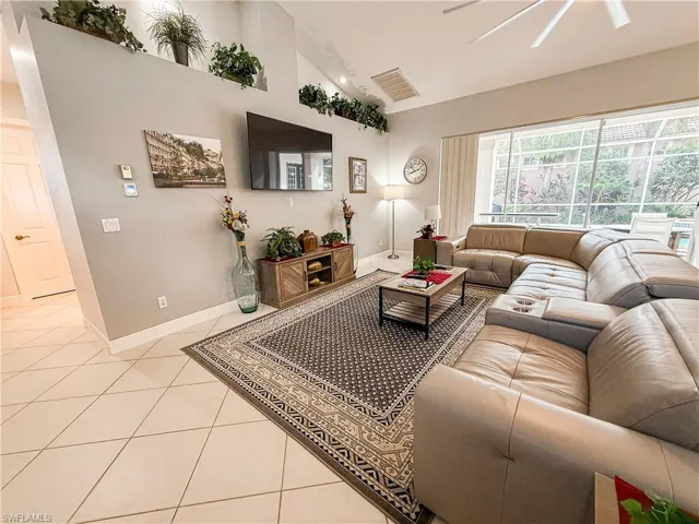 Living area featuring light tile patterned floors, high vaulted ceiling, and ceiling fan
