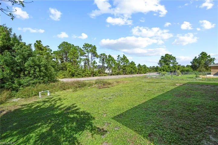 View of grassy yard with view of wooded area