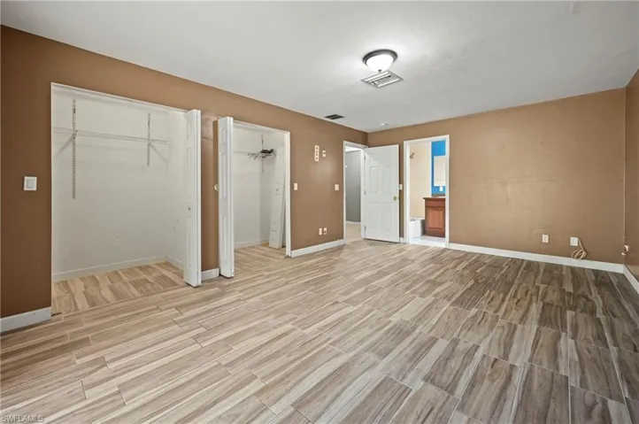 Unfurnished bedroom featuring two closets, wood tiled floors, and ensuite bathroom