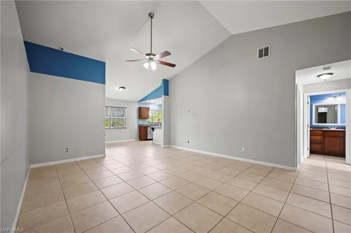 Unfurnished living room featuring light tile patterned floors, high vaulted ceiling, and a ceiling fan