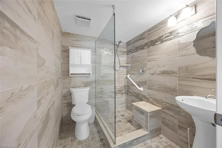 Bathroom with tile walls, walk in shower, and light tile patterned flooring