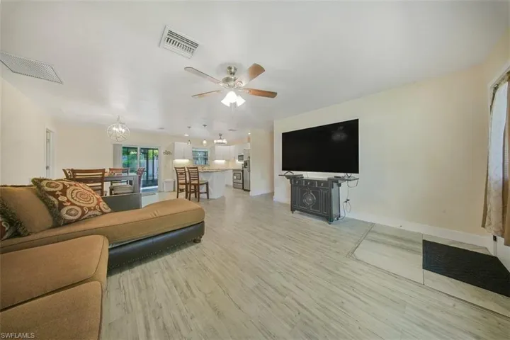 Living area with light wood-style flooring, ceiling fan, and a chandelier