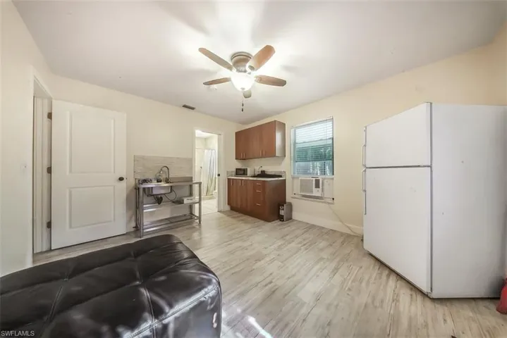 Kitchen with freestanding refrigerator, light wood-style floors, a ceiling fan, light countertops, and brown cabinets