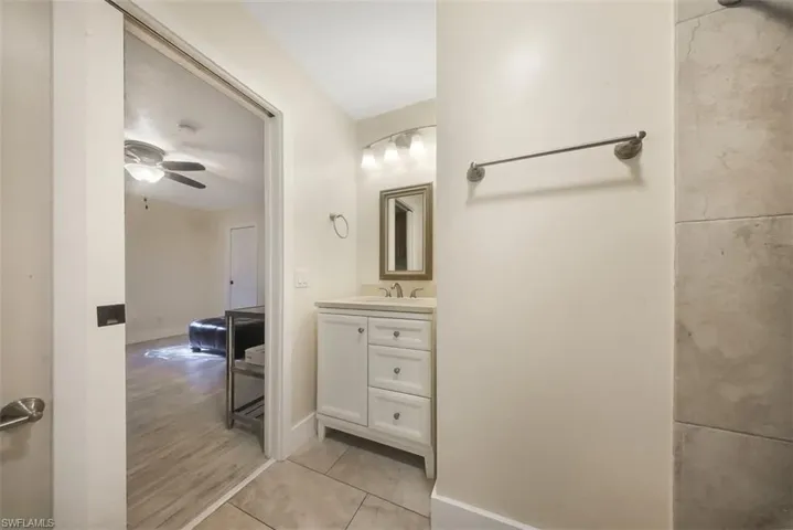 Half bath with vanity, ceiling fan, and light tile patterned flooring