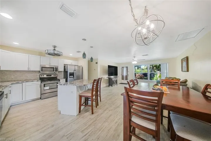 Dining room featuring a ceiling fan, light wood finished floors, and a chandelier