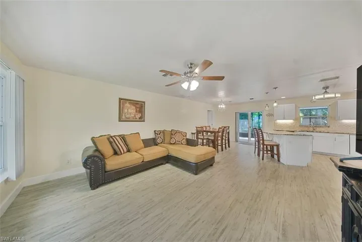 Living area with light wood finished floors, a chandelier, and a ceiling fan