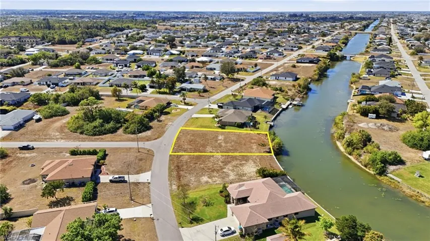 Aerial view of residential area featuring property boundaries highlighted and a nearby body of water
