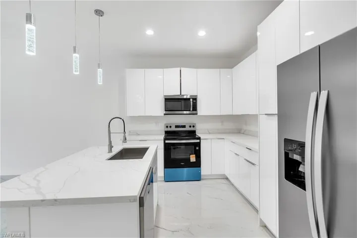 Kitchen with stainless steel appliances, white cabinets, a peninsula, and modern cabinets