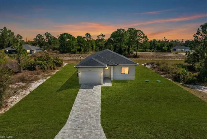 Single story home with a front yard, driveway, roof with shingles, and a garage