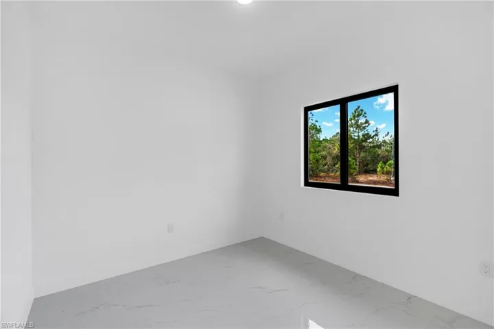 Unfurnished room featuring light marble finish flooring and baseboards