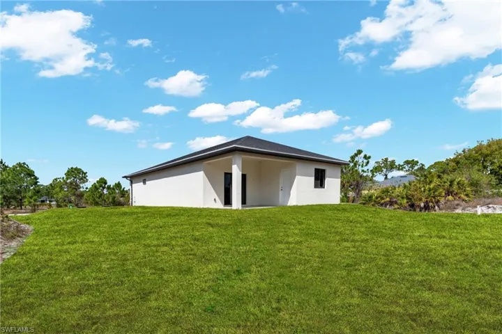 View of side of property featuring a yard, stucco siding, and a patio