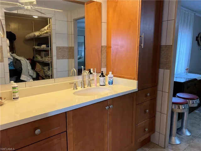 Bathroom featuring tile patterned flooring, ceiling fan, and vanity