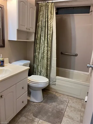 Bathroom with vanity, toilet, shower / tub combo, and tile patterned floors