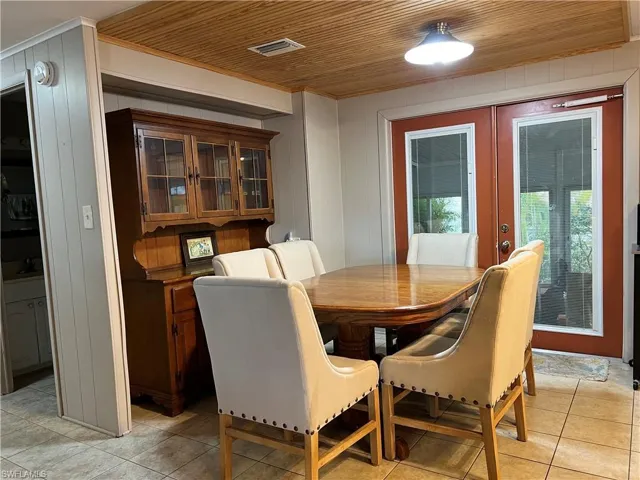 Dining space featuring dining table and chairs that convey with sale floors, french doors, wooden ceiling accent.