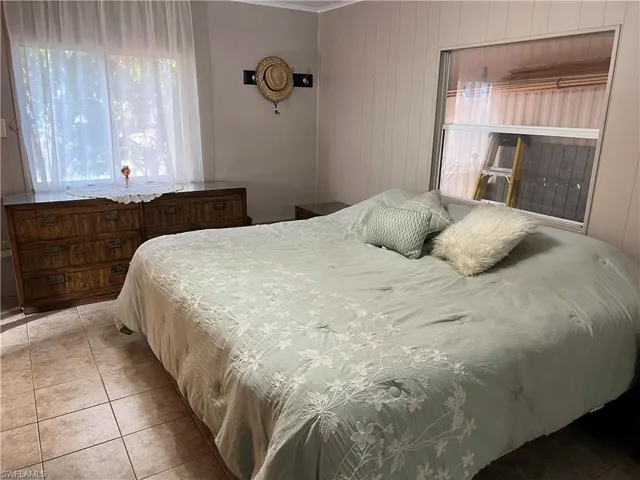 Bedroom with light tile patterned floors and ornamental molding