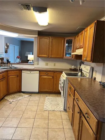 Kitchen with dishwasher, stove, a sink, dark countertops, and brown cabinets