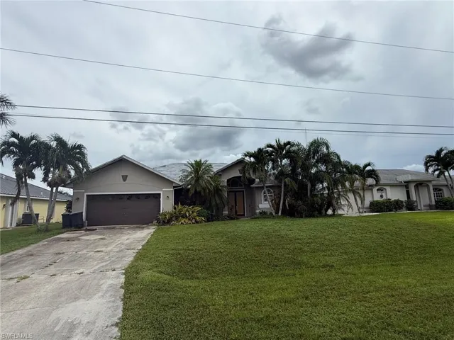 Single story home featuring concrete driveway, a front yard, stucco siding, and a garage