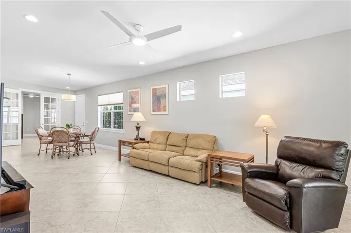 Living room with a ceiling fan, recessed lighting, and light tile patterned floors
