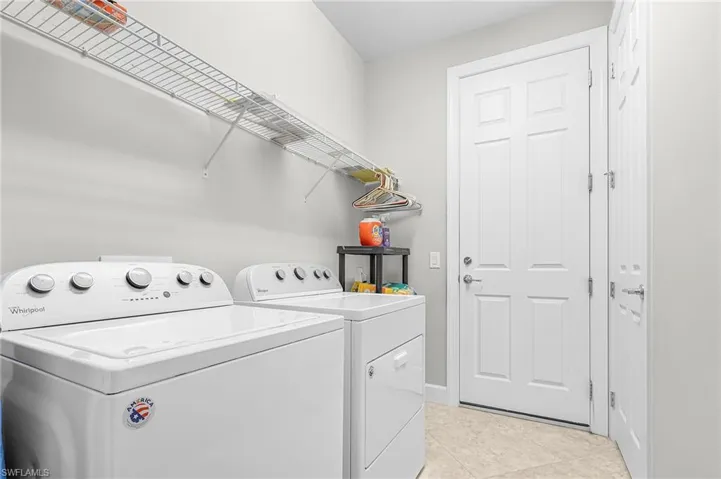 Laundry area with washing machine and dryer and light tile patterned floors