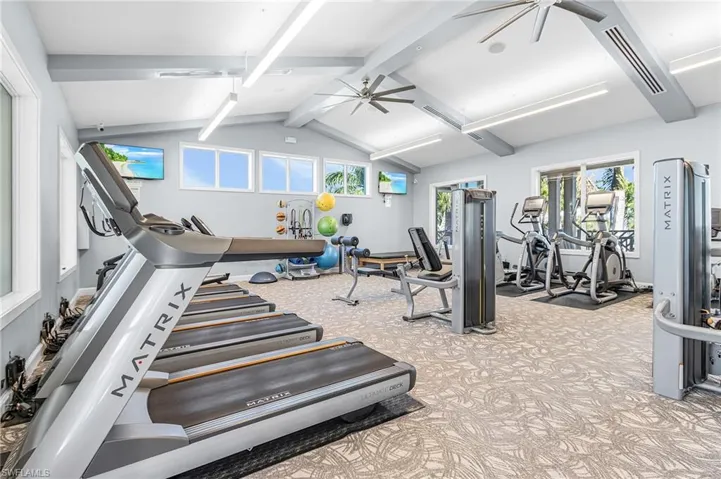 Gym with a ceiling fan and beamed ceiling