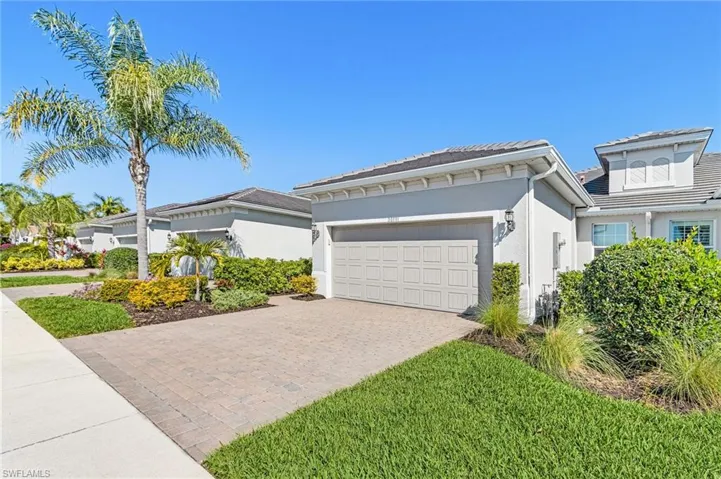 View of front of home featuring stucco siding, decorative driveway, and a garage