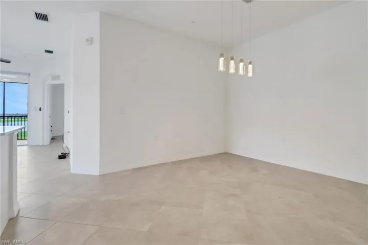 Open concept living space featuring light-toned tile flooring, recessed lighting, and a contemporary linear chandelier with four individual glass pendants