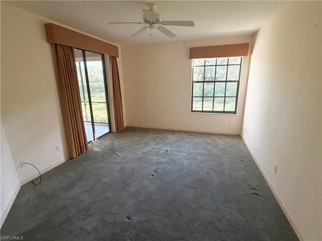 Unfurnished room featuring dark colored carpet and a ceiling fan