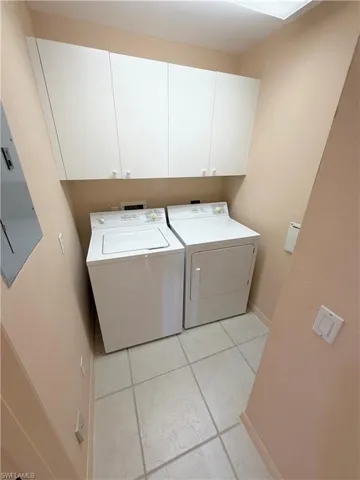 Laundry room with light tile patterned flooring, cabinet space, and separate washer and dryer