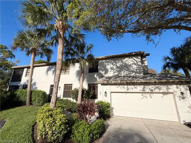 View of front of house featuring an attached garage, stucco siding, and driveway