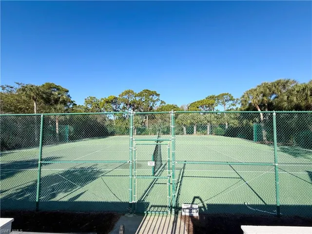 View of tennis court featuring a gate