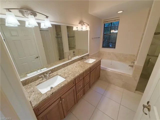 Full bath featuring double vanity, light tile patterned floors, a bath, and a shower stall