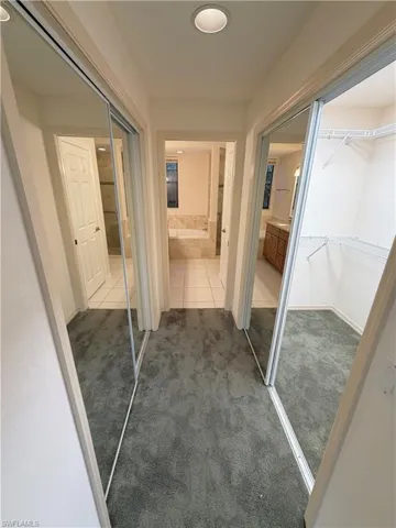 Hallway featuring carpet flooring and tile patterned flooring