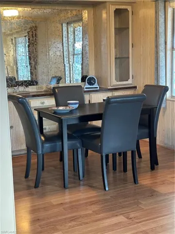Dining space with light wood-type flooring, healthy amount of natural light, and wooden walls