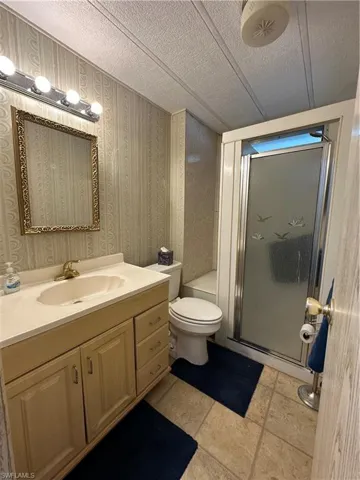 Bathroom with a shower stall, vanity, a textured ceiling