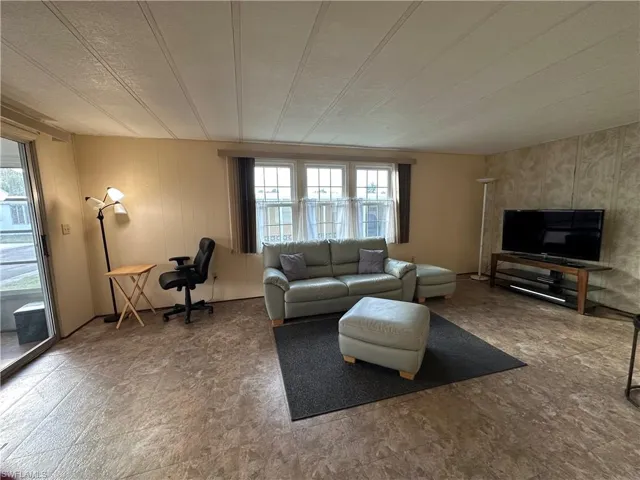Living room featuring a textured ceiling and wood walls