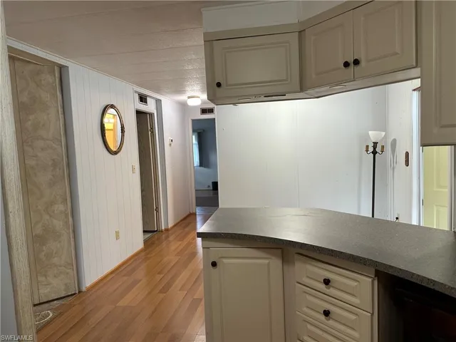 Kitchen with dark countertops, light wood finished floors, cream cabinets, and wood walls