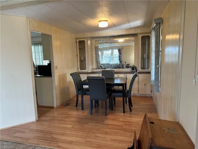 Dining area with wooden walls and light wood-type flooring