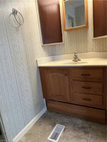 Bathroom with vanity and wallpapered walls