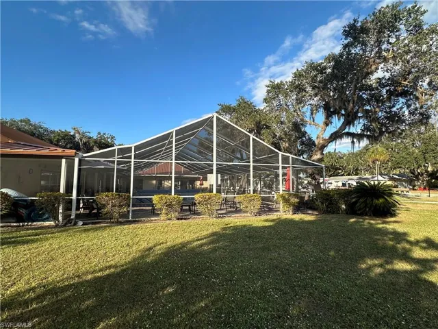 View of green lawn with glass enclosure, a patio area, and a sunroom