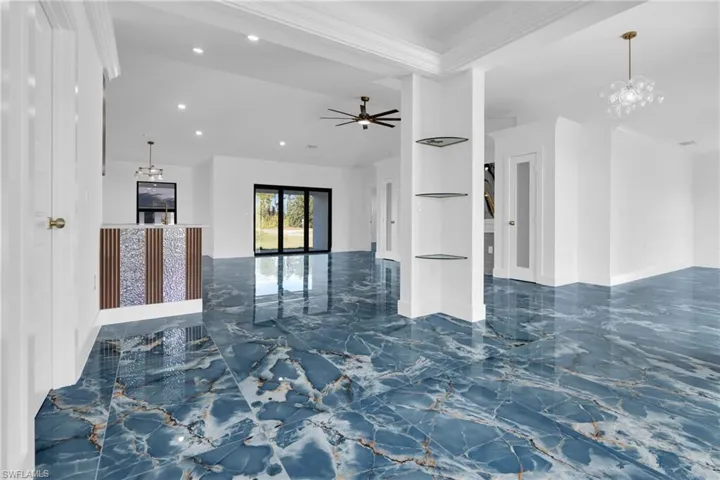 Unfurnished living room featuring a chandelier, dark marble finish flooring, recessed lighting, ceiling fan, and ornamental molding