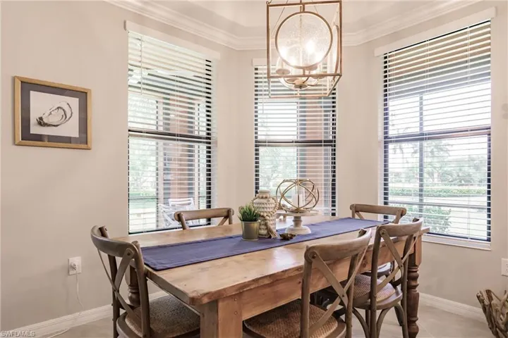Tiled dining space with a healthy amount of sunlight, a notable chandelier, and ornamental molding