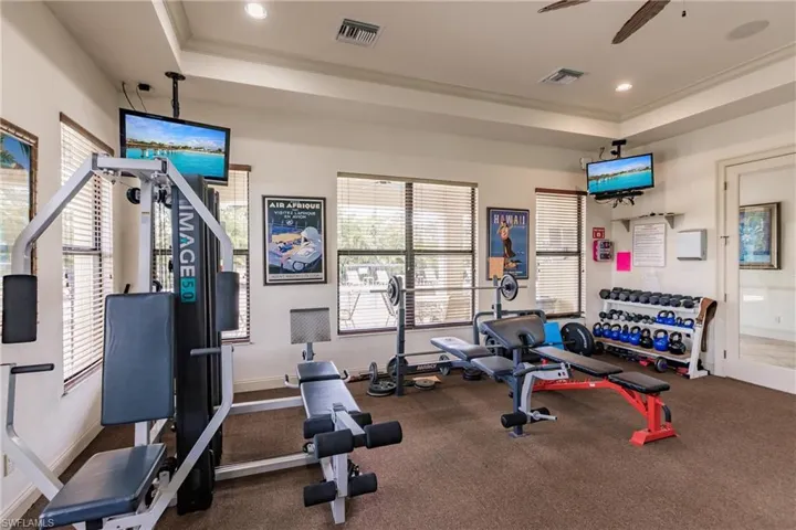 Workout area featuring ceiling fan, carpet, and a tray ceiling