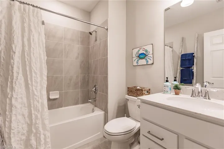 Full bathroom with vanity, toilet, shower / bathtub combination with curtain, and tile patterned flooring