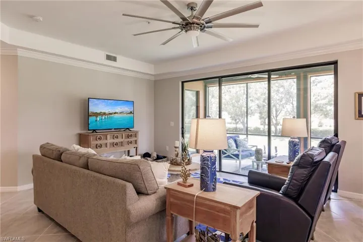 Living room with ornamental molding, light tile patterned floors, and ceiling fan